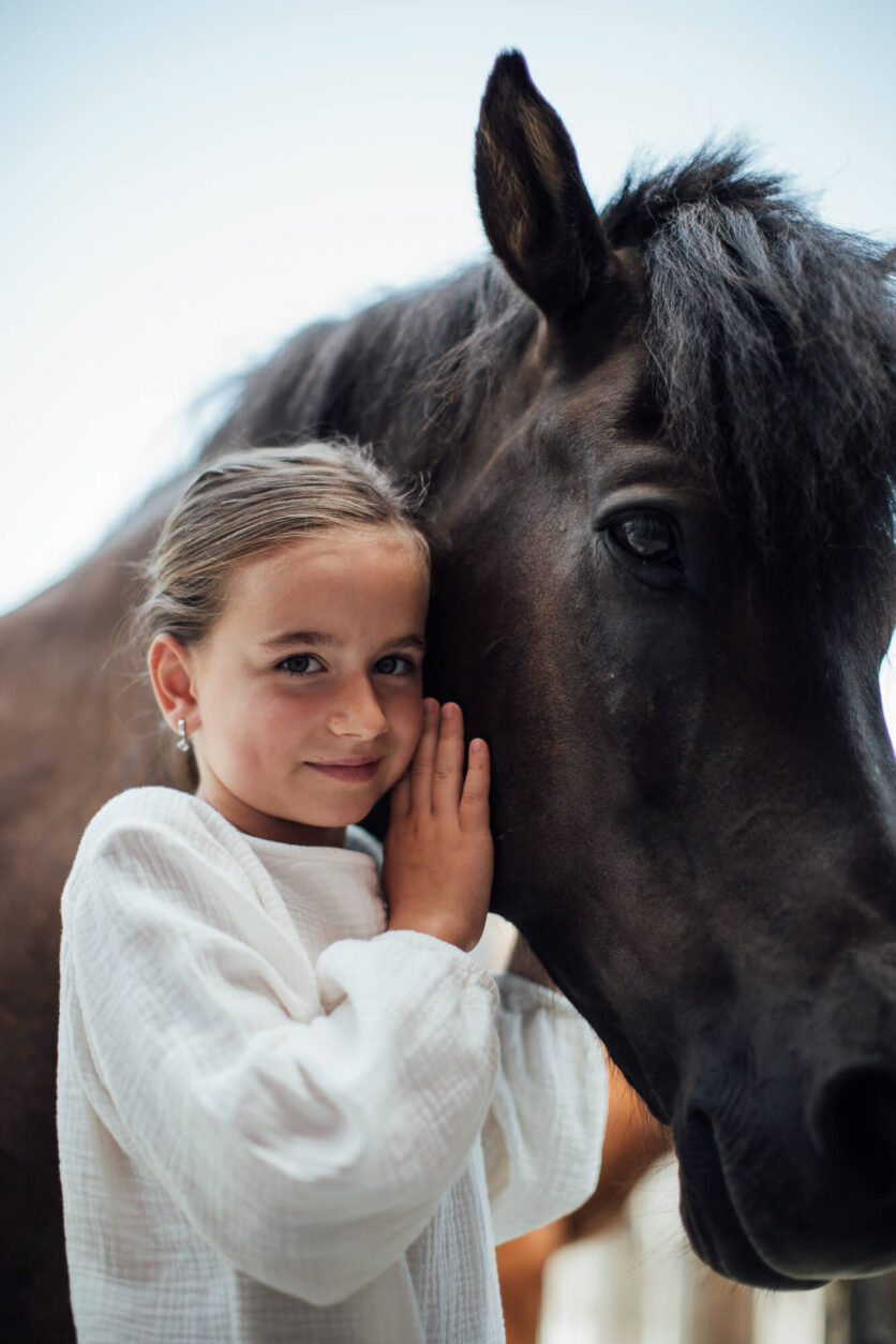 Mädchen kuschelt sich an Pferd