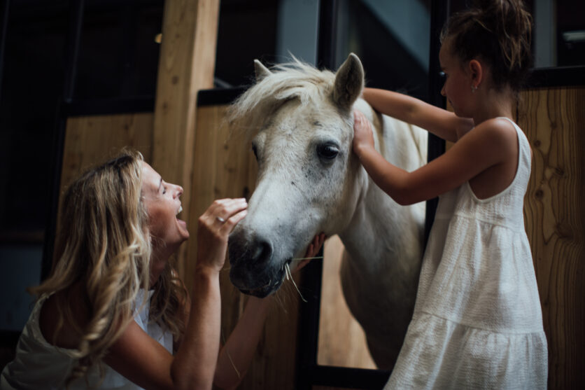 Mutter und Tochter streicheln Pferd