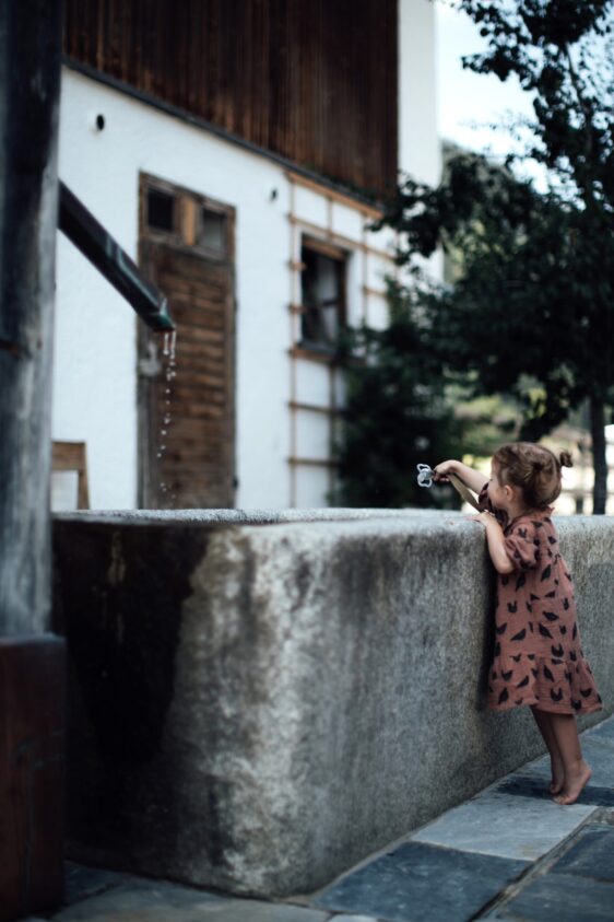 mädchen auf zehenspitzen vor brunnen